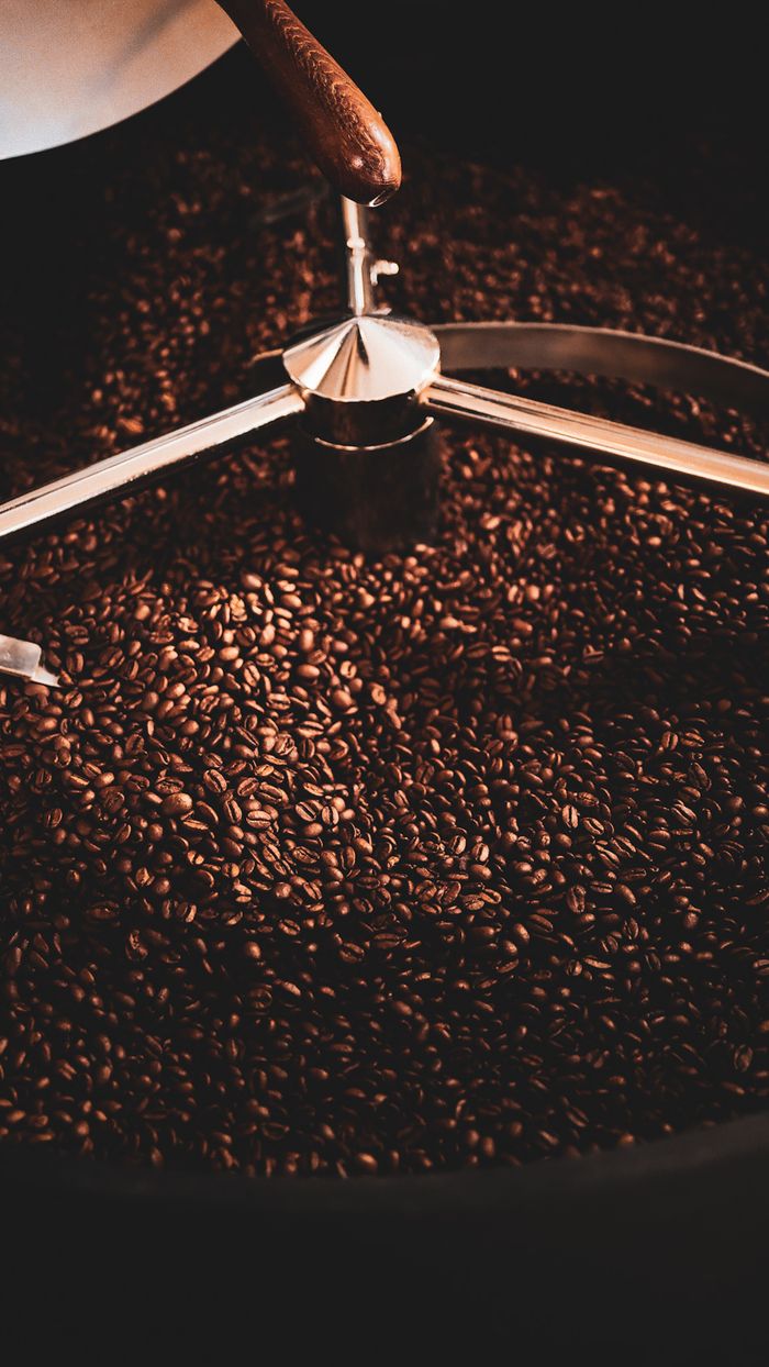 A close-up view of freshly roasted coffee beans in a coffee roaster with warm lighting.