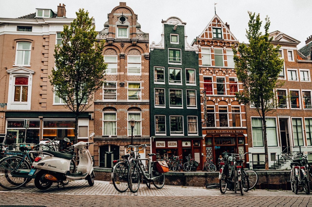 Scenic view of Amsterdam's iconic canal street with bicycles and historic buildings under trees.